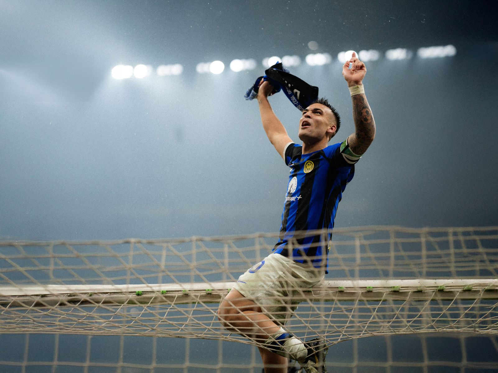 Fotografia sportiva di un calciatore dell’Inter che esulta sopra la rete dopo il gol. 