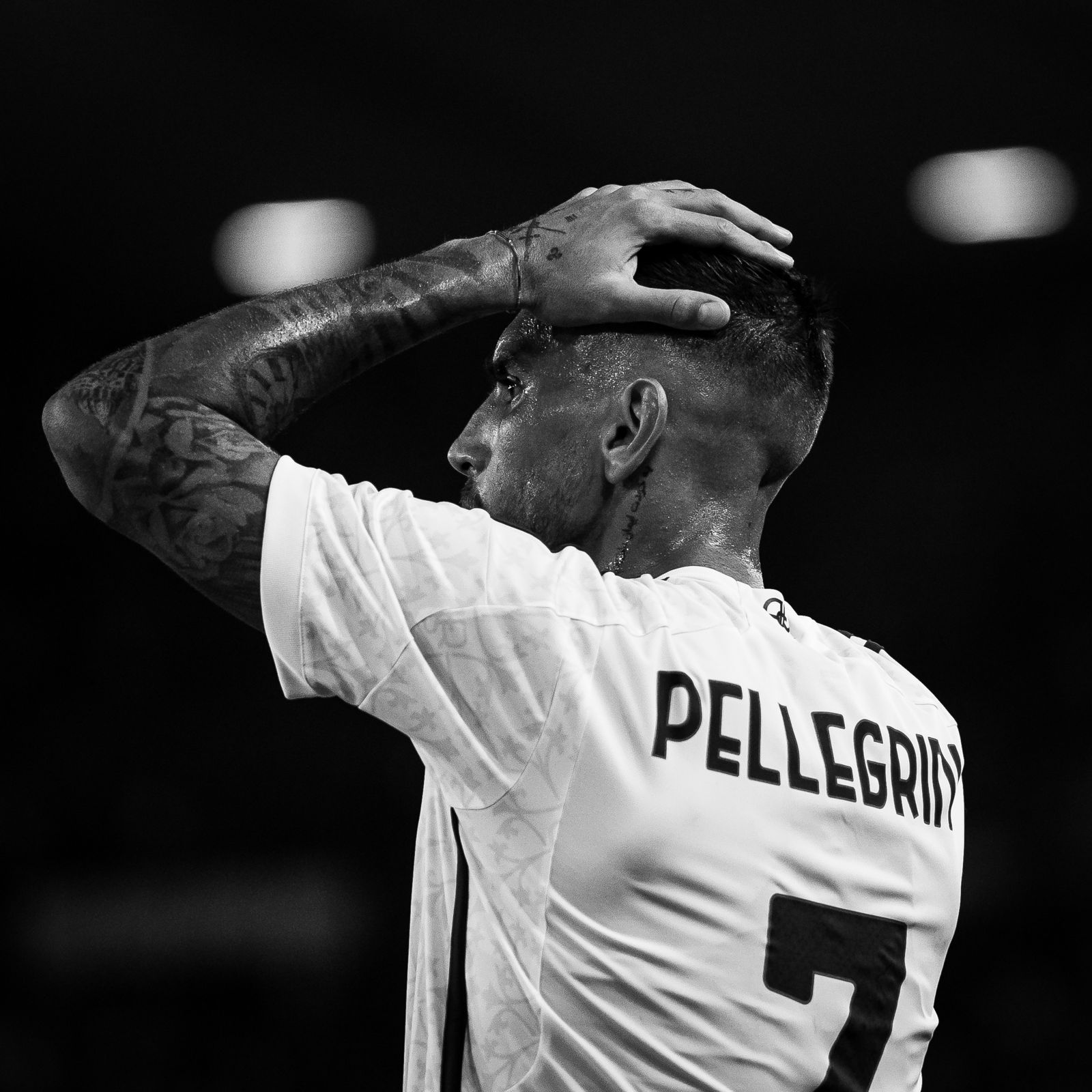 Fotografia sportiva in bianco e nero di calciatore di spalle durante la partita, momento di concentrazione catturato da fotografo sportivo professionista.